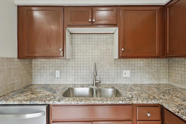 Kitchen with a sink, dishwasher, backsplash, and light stone countertops | Image 15