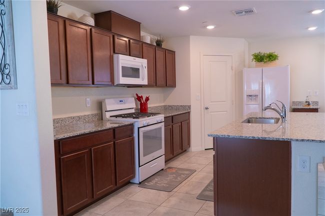 Kitchen with a sink, visible vents, recessed lighting, white appliances, and light stone counters | Image 20