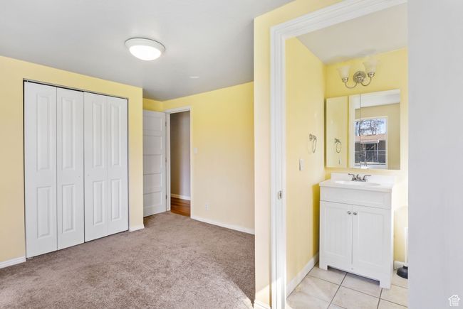 Bedroom with a closet, light colored carpet, a sink, and baseboards | Image 36