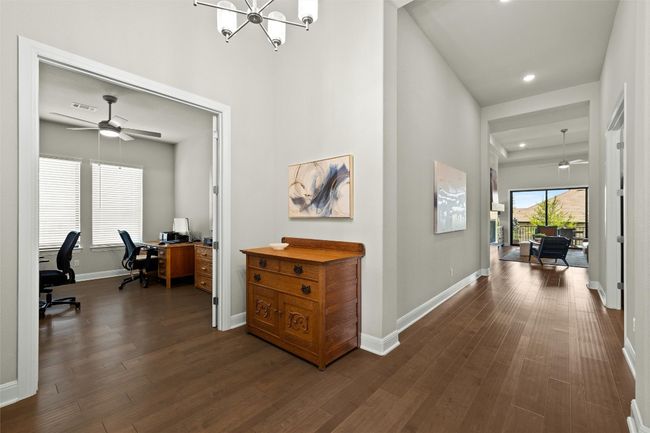 Hallway with a desk, dark wood finished floors, recessed lighting, and a chandelier | Image 6