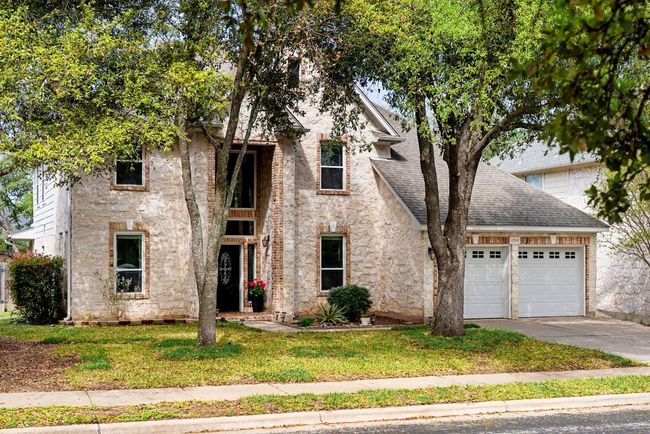 View of front of house with roof with shingles, an attached garage, a front lawn, and concrete driveway. This is a stone exterior. | Image 29