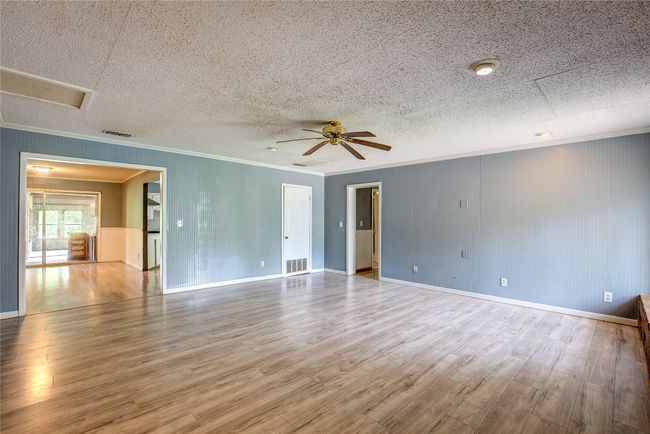 Unfurnished room with wood finished floors, ornamental molding, ceiling fan, baseboards, and a textured ceiling | Image 11