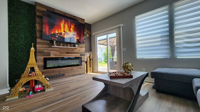 living area featuring a glass covered fireplace and wood finished floors | Image 9