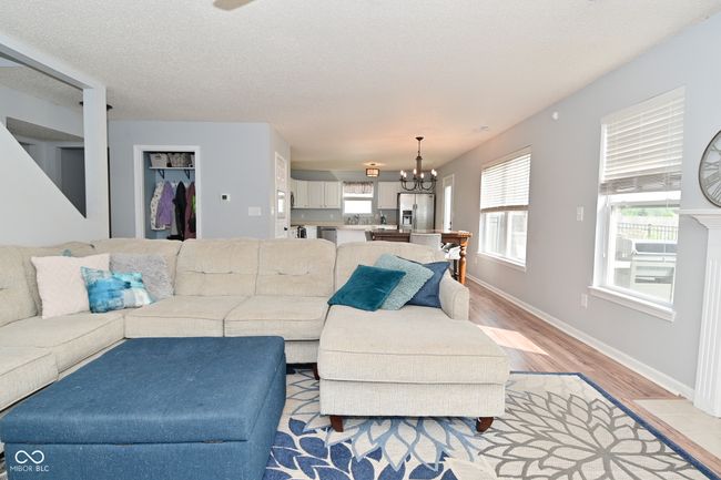 living area with a chandelier, light wood-type flooring, healthy amount of natural light, and baseboards | Image 10