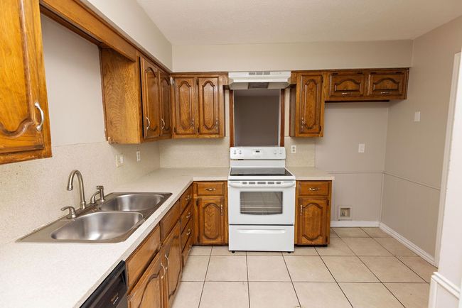 Kitchen featuring white electric range, a sink, under cabinet range hood, and light countertops | Image 9