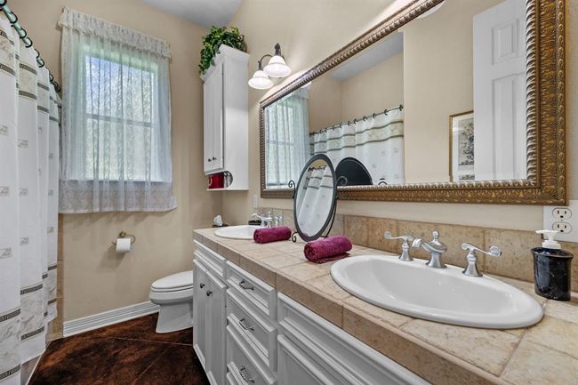 Bright bath with dual vanities, tile countertop, and a full-height tub/shower combo. | Image 30