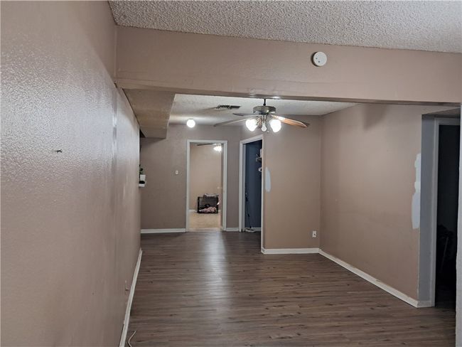 Spare room featuring a textured ceiling, wood finished floors, a ceiling fan, and a smoke detector | Image 7