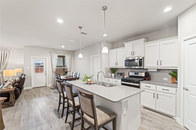 Kitchen with visible vents, light wood finished floors, a sink, stainless steel appliances, and tasteful backsplash | Image 6