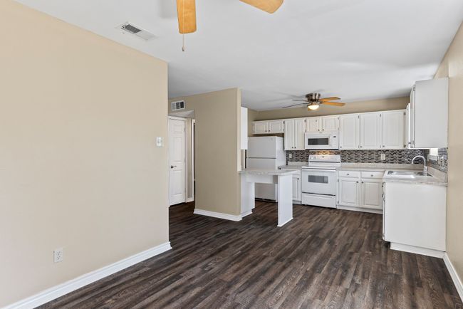 Kitchen with tasteful backsplash, white appliances, visible vents, and a sink | Image 15