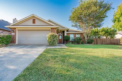 Ranch-style house with a front yard and a garage | Image 1