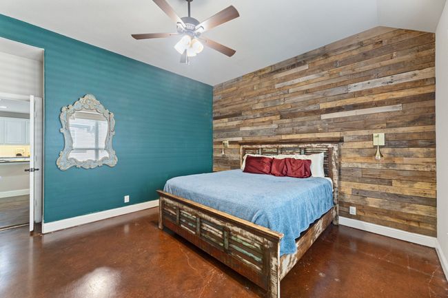 Bedroom with concrete flooring, vaulted ceiling, baseboards, arched walkways, and a barn door | Image 13