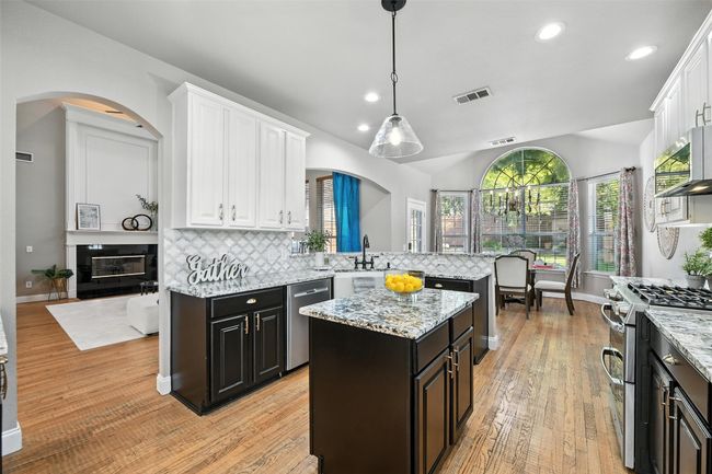 Kitchen with white cabinets, stainless steel appliances, arched walkways, backsplash, and recessed lighting | Image 8