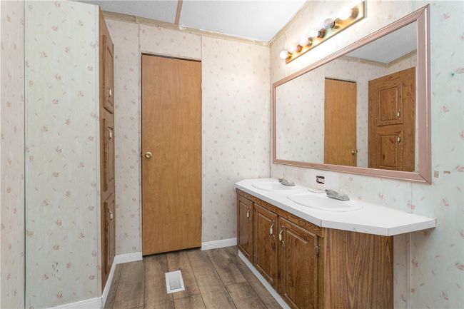 Bathroom with wood finished floors, double vanity, and wallpapered walls | Image 12
