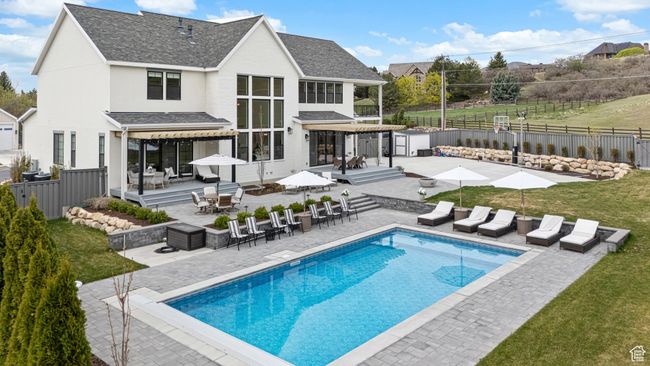 Back of property with a patio area, a fenced backyard, an outdoor structure, a fenced in pool, and a storage unit | Image 55