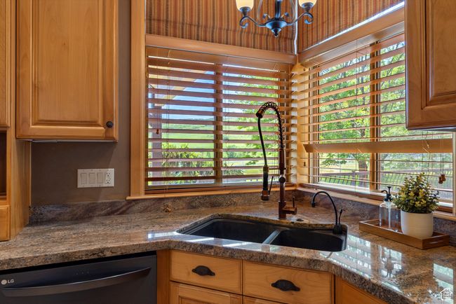 Kitchen with dishwasher, a sink, a chandelier, and dark stone countertops | Image 32