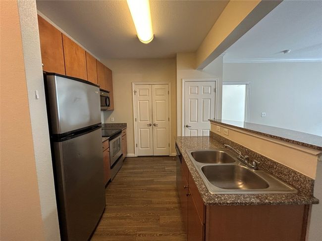 Kitchen with brown cabinets, dark countertops, stainless steel appliances, and a sink | Image 18