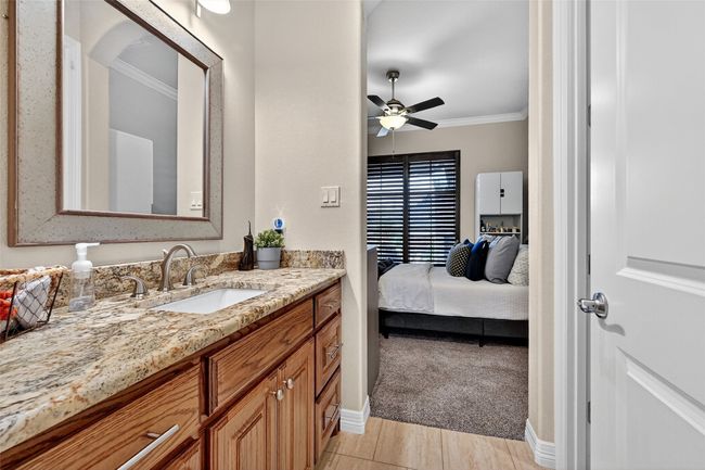 Ensuite bathroom featuring crown molding, vanity, a ceiling fan, and wood finished floors | Image 23