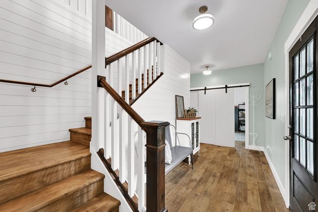 Entryway featuring a barn door, wood-type flooring, stairs, and wood walls | Image 6