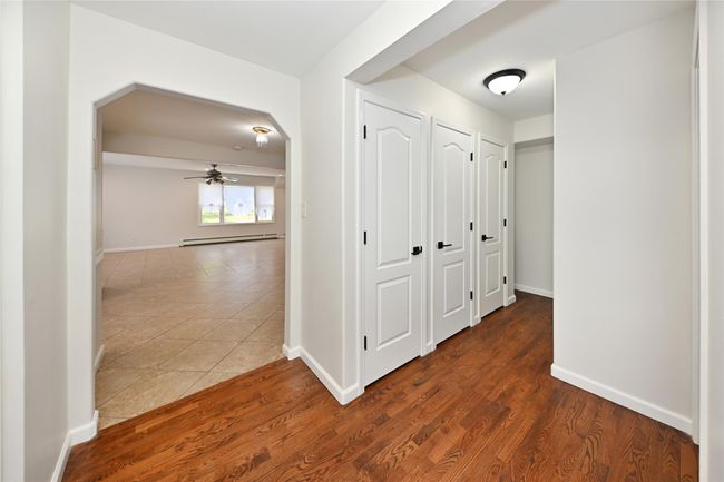 Hallway featuring wood finished floors, baseboards, baseboard heating, and arched walkways | Image 9