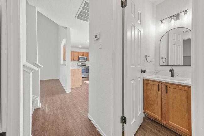 1/2 Bathroom off kitchen featuring wood finished floors, vanity, baseboards, and visible vents | Image 14