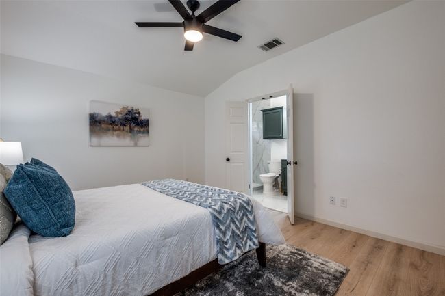Bedroom with visible vents, baseboards, ensuite bathroom, light wood finished floors, and lofted ceiling | Image 19