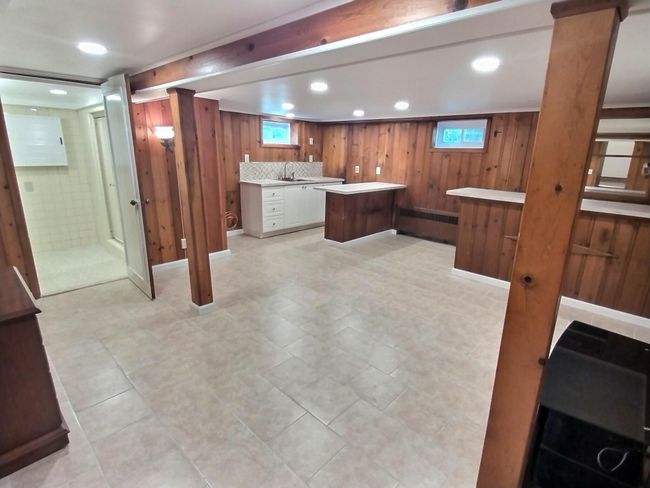 Kitchen featuring light countertops, wood walls, brown cabinets, a sink, and radiator | Image 26