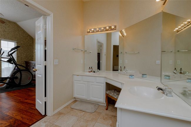 Full bath featuring double vanity, a sink, tile patterned floors, and vaulted ceiling | Image 25