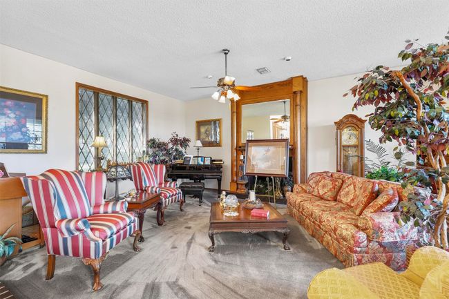 Living room with ceiling fan, carpet flooring, and a textured ceiling | Image 11