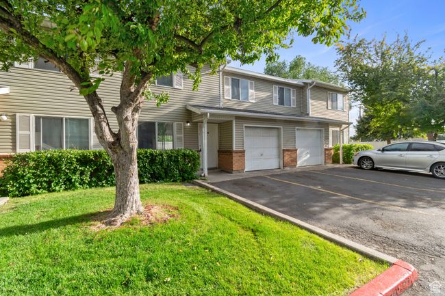 Townhome / multi-family property featuring asphalt driveway, a garage, brick siding, and a front yard | Image 31