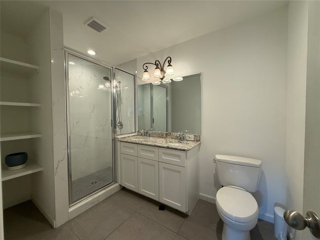 Full bathroom featuring a marble finish shower, double vanity, tile patterned floors, a chandelier, and recessed lighting | Image 15