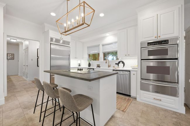 Kitchen with appliances with stainless steel finishes, a warming drawer, backsplash, ornamental molding, and a kitchen island | Image 9