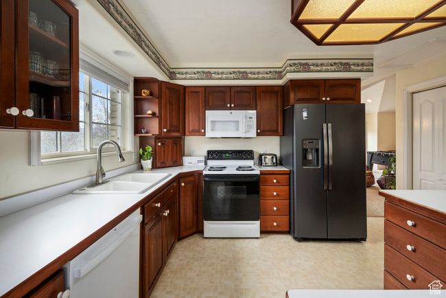 Kitchen with a sink, glass insert cabinets, white appliances, and light countertops | Image 18