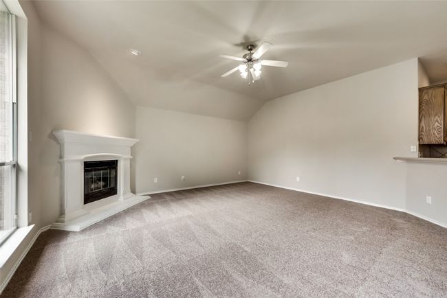 Unfurnished living room with carpet, ceiling fan, a glass covered fireplace, and vaulted ceiling | Image 19