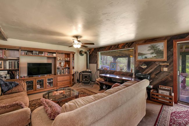 Living room with a wood stove, wooden walls, healthy amount of natural light, ceiling fan, and carpet floors | Image 38