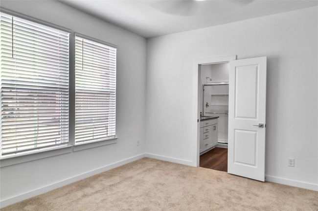 Unfurnished bedroom featuring a walk in closet, carpet flooring, and baseboards | Image 7
