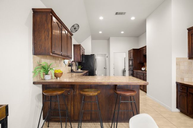Kitchen featuring decorative backsplash, a breakfast bar, a peninsula, dark brown cabinets, and recessed lighting | Image 15