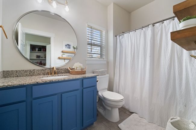 Bathroom featuring toilet, tile patterned flooring, vanity, and a shower with shower curtain | Image 9