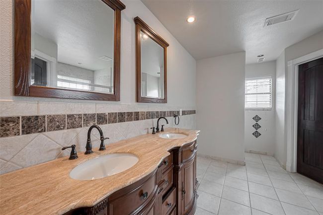 This dual vanity setup offers plenty of space and storage with beautifully detailed cabinetry and an extended granite counter—perfect for morning routines. | Image 27