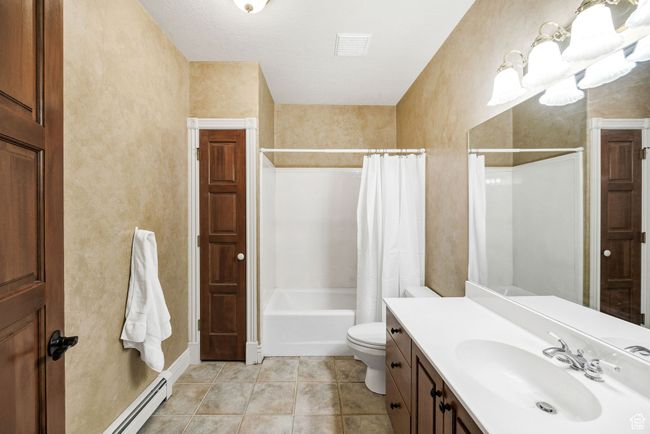 Bathroom with shower / bath combo, vanity, tile patterned flooring, and a baseboard heating unit | Image 71