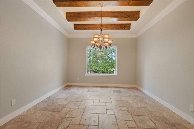 Unfurnished room featuring stone tile floors, a chandelier, a tray ceiling, baseboards, and beam ceiling | Image 6