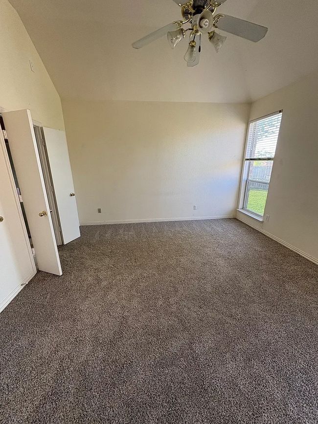 Carpeted spare room featuring a ceiling fan and lofted ceiling | Image 16