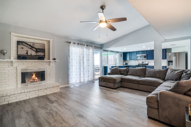 Living area featuring ceiling fan, lofted ceiling, a fireplace, and wood finished floors | Image 7