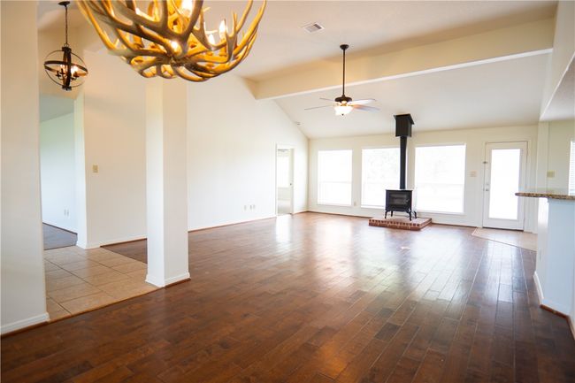 Unfurnished living room featuring a wood stove, a chandelier, dark wood-type flooring, and a ceiling fan | Image 21