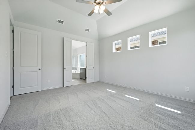 Unfurnished bedroom with carpet, high vaulted ceiling, ensuite bath, and ceiling fan | Image 19