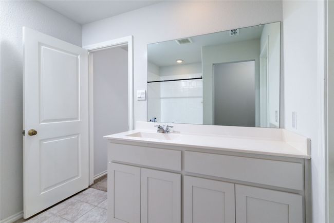 Bathroom with vanity, a shower, tile patterned floors, and baseboards | Image 24