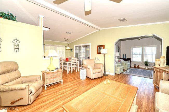Living room with ceiling fan, wood-type flooring, crown molding, and vaulted ceiling | Image 12