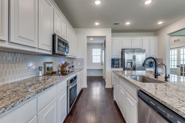 Kitchen featuring appliances with stainless steel finishes, white cabinetry, dark wood-type flooring, decorative backsplash, and healthy amount of natural light | Image 8