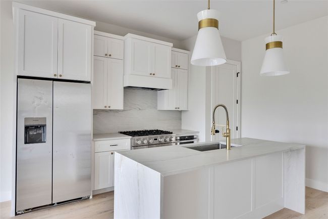 Kitchen featuring white refrigerator with ice dispenser, a sink, backsplash, and light wood finished floors | Image 26