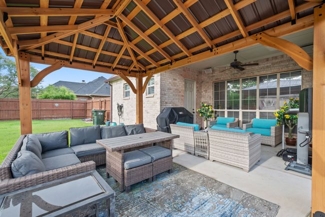 Fenced backyard with outdoor lounge area, area for grilling, ceiling fan, and a patio | Image 9