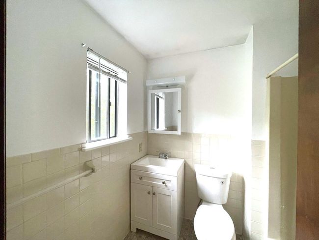 Bathroom with tile walls, vanity, wainscoting, and a shower | Image 12